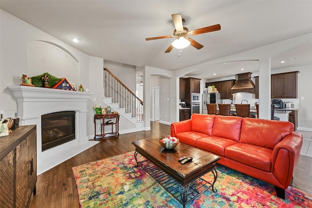 living room featuring baseboards, a fireplace with flush hearth, recessed lighting, stairs, and dark wood-type flooring