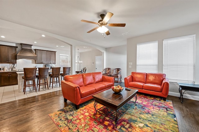 living area featuring visible vents, baseboards, light wood-style flooring, recessed lighting, and arched walkways