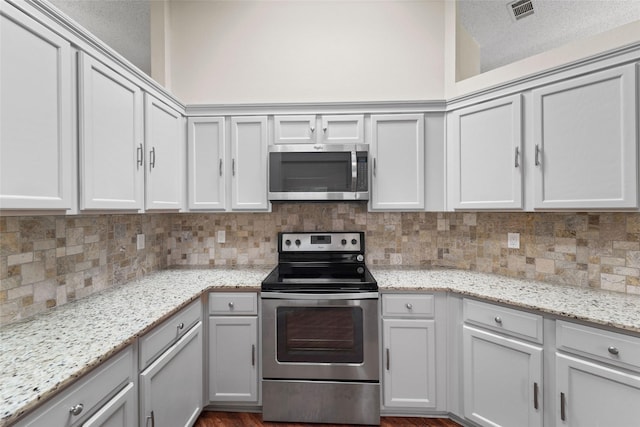 kitchen with tasteful backsplash, visible vents, appliances with stainless steel finishes, and light stone countertops