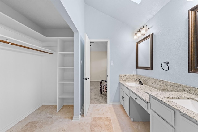 full bathroom featuring double vanity, a spacious closet, baseboards, and a sink