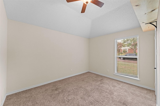 spare room with ceiling fan, baseboards, vaulted ceiling, carpet flooring, and a textured ceiling