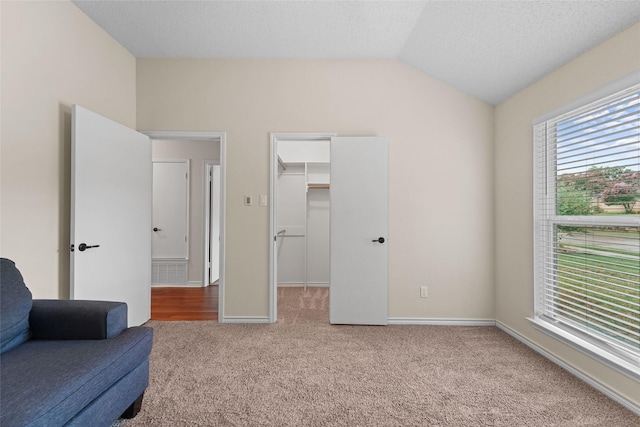 sitting room with vaulted ceiling, carpet, baseboards, and a textured ceiling