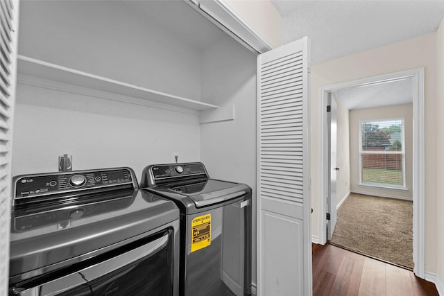 laundry area with dark wood finished floors, laundry area, washer and dryer, and baseboards