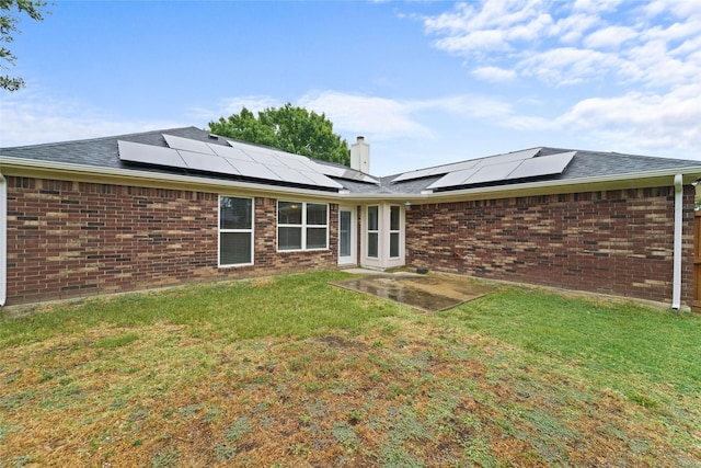 back of property with a lawn, brick siding, and a chimney