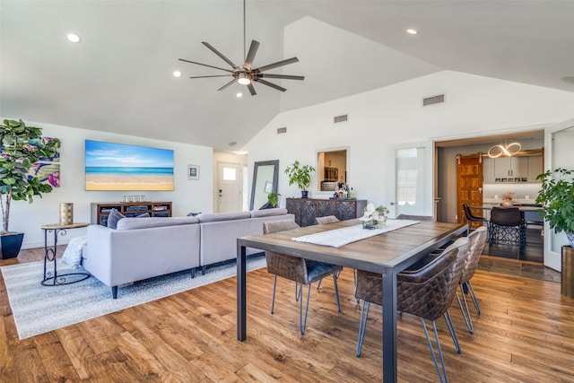 dining area featuring a ceiling fan, light wood-style floors, visible vents, and high vaulted ceiling