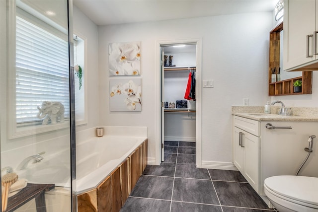 full bath featuring a walk in closet, toilet, a garden tub, tile patterned floors, and vanity