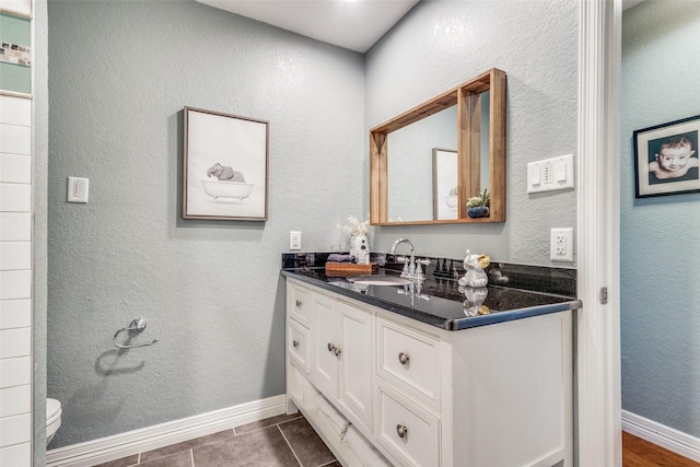 bathroom with tile patterned floors, baseboards, toilet, and vanity