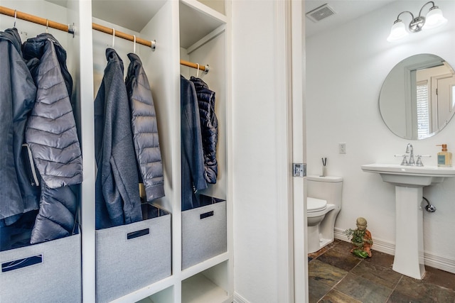 bathroom featuring visible vents, toilet, stone finish flooring, and baseboards