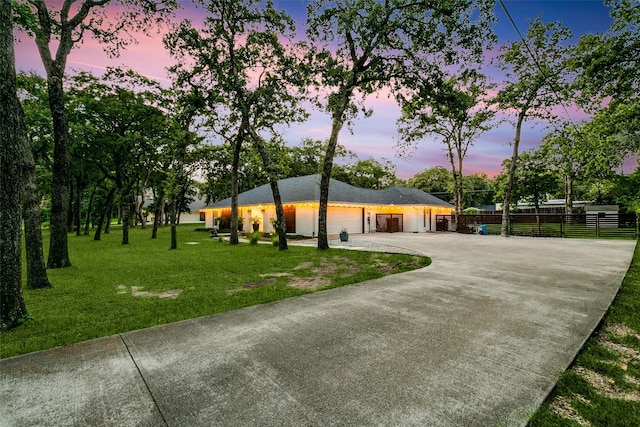 ranch-style house featuring a yard, fence, driveway, and an attached garage