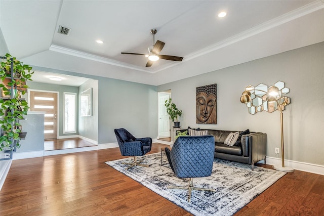 living area featuring a ceiling fan, wood finished floors, visible vents, baseboards, and crown molding