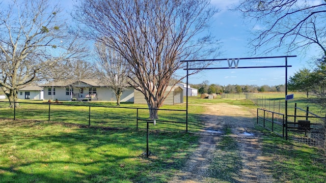 view of yard with a rural view, fence, and driveway