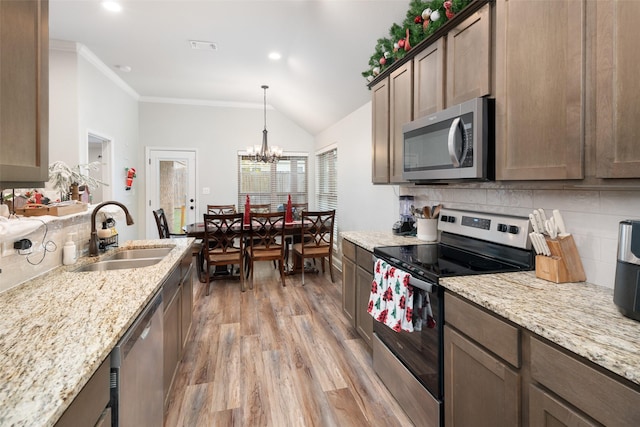 kitchen featuring light wood-type flooring, a sink, appliances with stainless steel finishes, crown molding, and tasteful backsplash