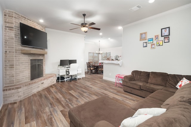 living area with a fireplace, crown molding, wood finished floors, and visible vents