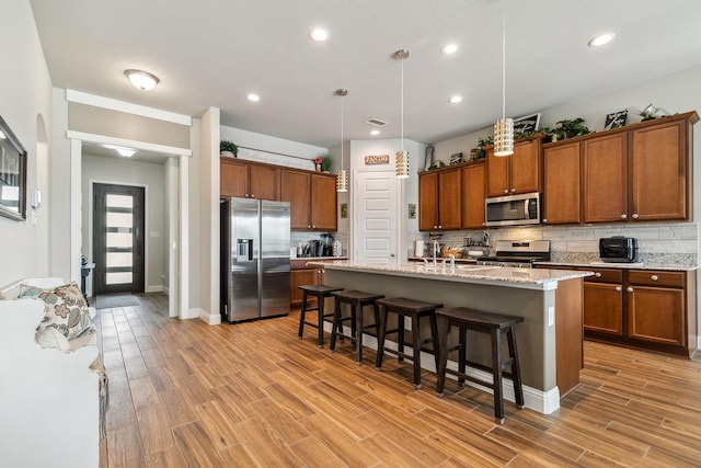 kitchen featuring stainless steel appliances, backsplash, a breakfast bar area, and brown cabinetry