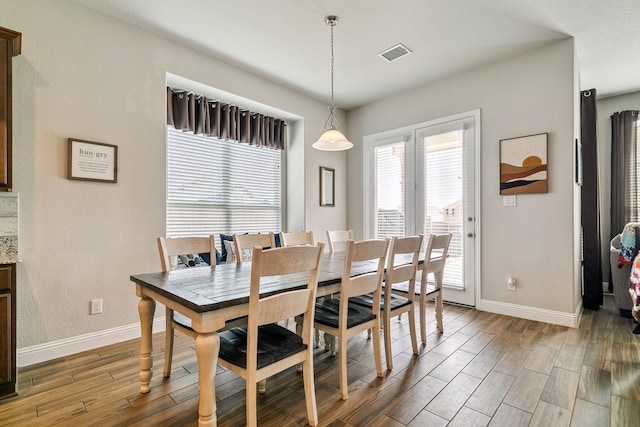 dining space featuring wood finished floors, visible vents, and baseboards