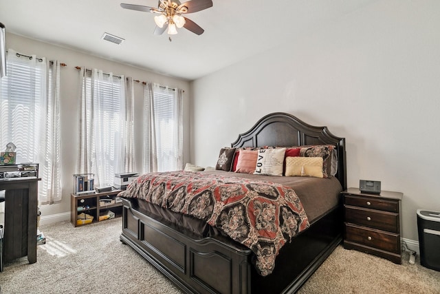 bedroom with visible vents, multiple windows, light colored carpet, and baseboards