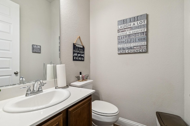 bathroom with vanity, toilet, and a textured wall