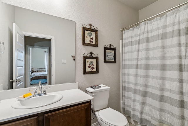 ensuite bathroom featuring connected bathroom, toilet, a shower with curtain, a textured wall, and vanity