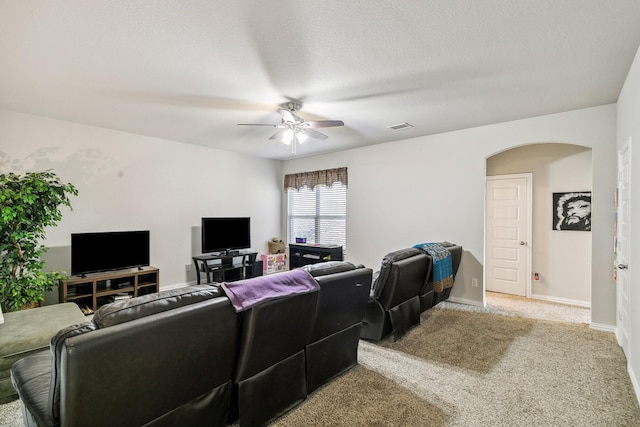 living room featuring carpet, baseboards, visible vents, a ceiling fan, and arched walkways