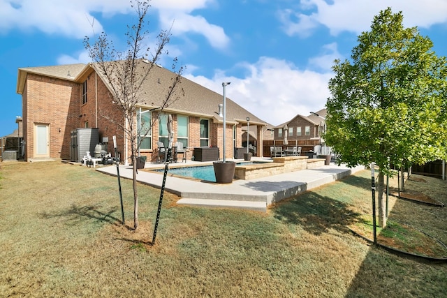 rear view of property with brick siding, a lawn, and a patio area