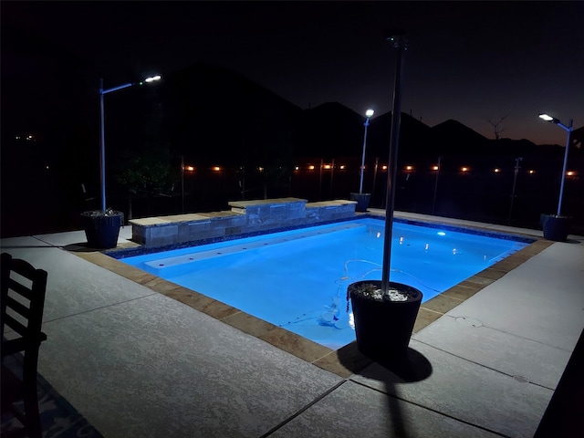 pool at twilight featuring a patio and an outdoor pool