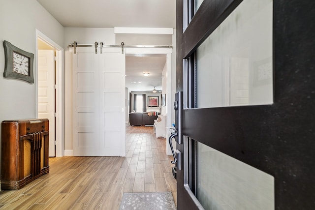 corridor featuring a barn door and light wood-style flooring