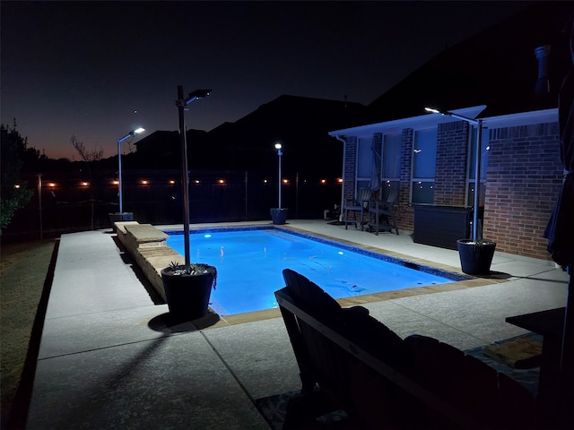 pool at twilight with a patio and a fenced in pool