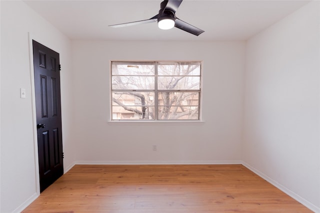 empty room featuring light wood finished floors, a ceiling fan, and baseboards