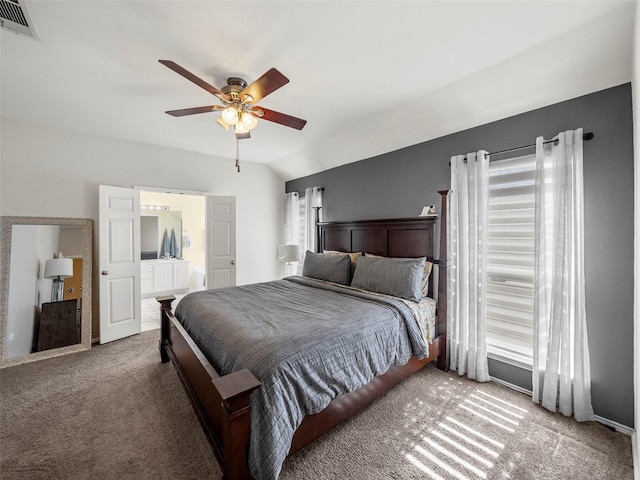 carpeted bedroom with visible vents, lofted ceiling, connected bathroom, and a ceiling fan