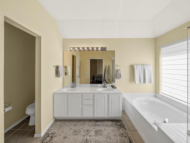 ensuite bathroom with tile patterned flooring, toilet, a bath, and double vanity