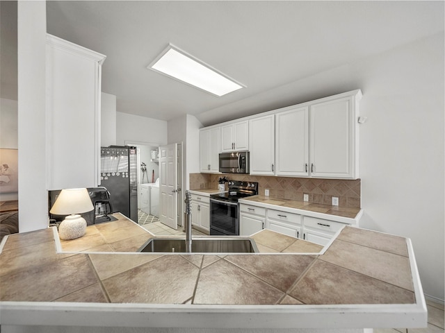 kitchen featuring stainless steel appliances, a sink, backsplash, independent washer and dryer, and white cabinets