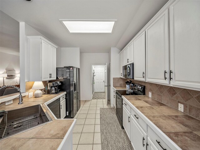 kitchen featuring electric range, stainless steel refrigerator with ice dispenser, a sink, white cabinetry, and backsplash