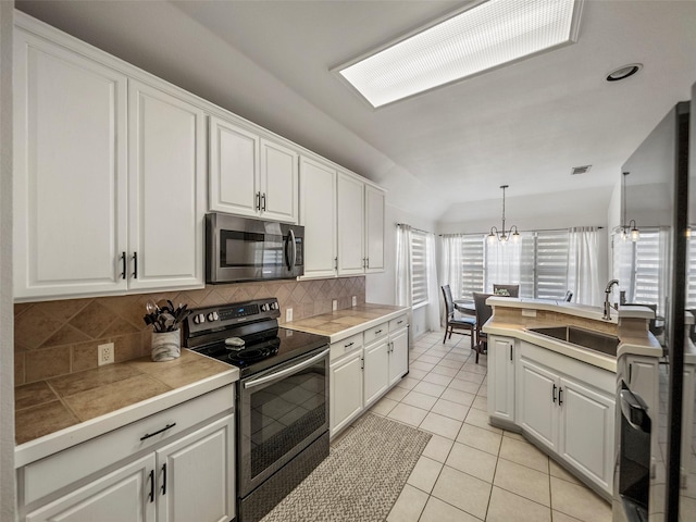 kitchen featuring stainless steel appliances, decorative backsplash, white cabinetry, light tile patterned floors, and lofted ceiling