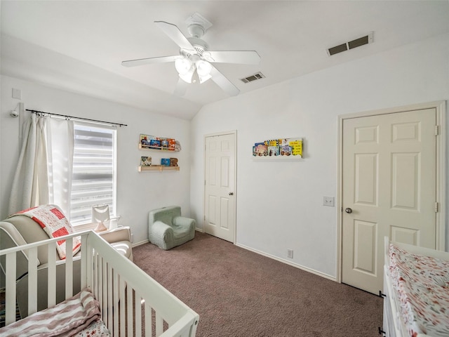 carpeted bedroom with visible vents, lofted ceiling, a nursery area, and ceiling fan