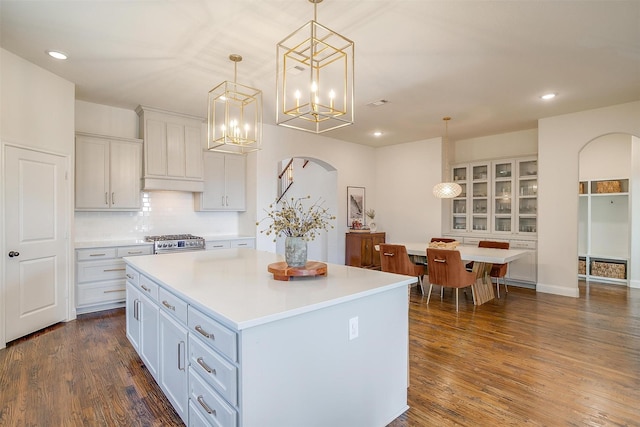 kitchen featuring arched walkways, dark wood-style floors, and light countertops