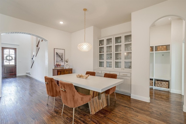 dining space with recessed lighting, baseboards, arched walkways, and dark wood finished floors