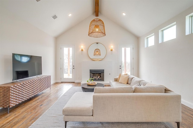 living area featuring baseboards, beam ceiling, a fireplace, wood finished floors, and high vaulted ceiling