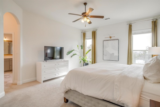 bedroom featuring visible vents, baseboards, light colored carpet, arched walkways, and a ceiling fan