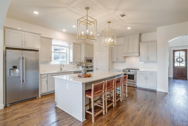 kitchen with dark wood-style floors, a sink, light countertops, appliances with stainless steel finishes, and a center island