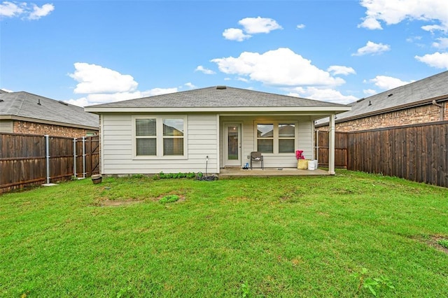 rear view of property featuring a patio, a yard, and a fenced backyard