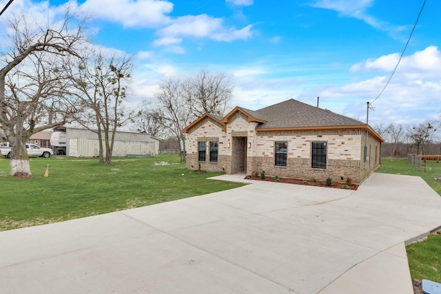 view of front of property with brick siding, a front yard, and a shingled roof