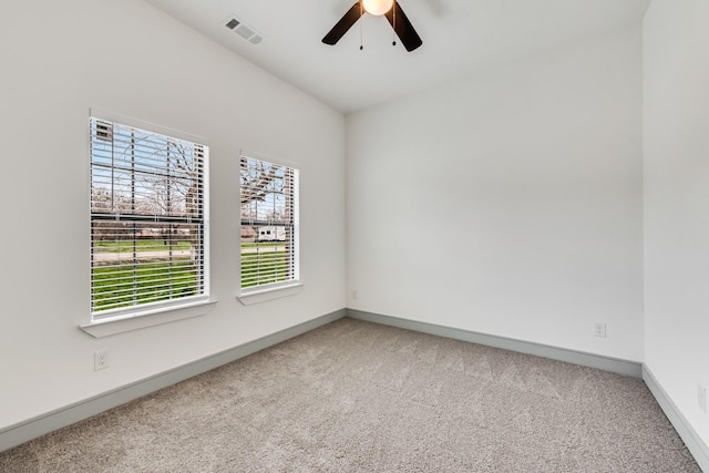 empty room featuring visible vents, carpet floors, baseboards, and ceiling fan