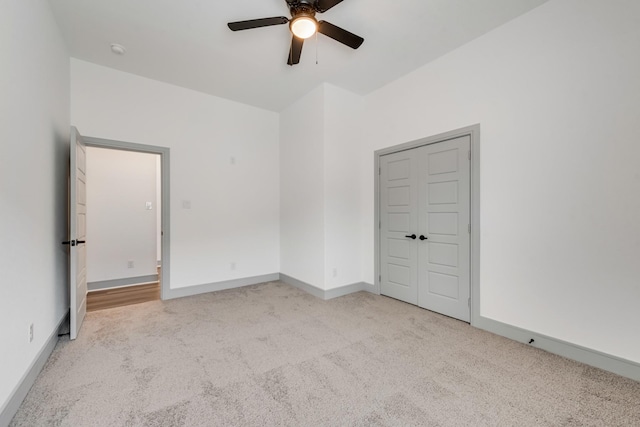 carpeted spare room featuring baseboards and ceiling fan