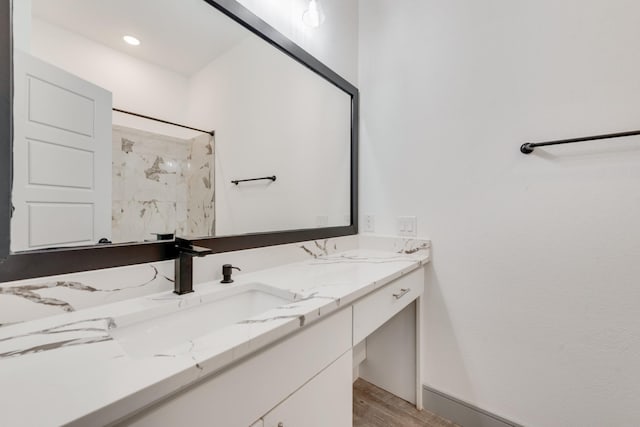 full bath with walk in shower, wood finished floors, and vanity