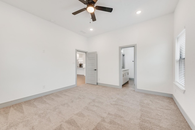 unfurnished bedroom featuring light carpet, recessed lighting, ensuite bathroom, and baseboards