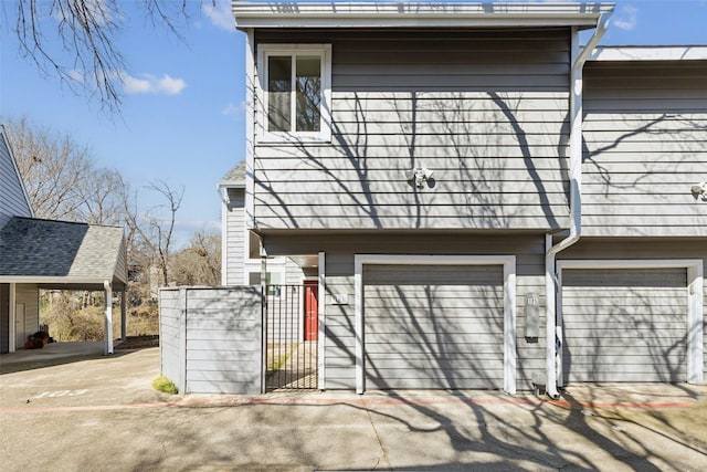 exterior space featuring driveway, an attached garage, and a gate