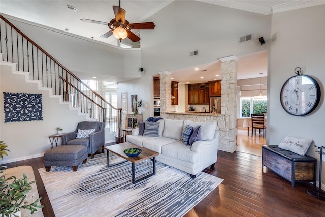 living room featuring crown molding, dark wood-style floors, visible vents, and ornate columns