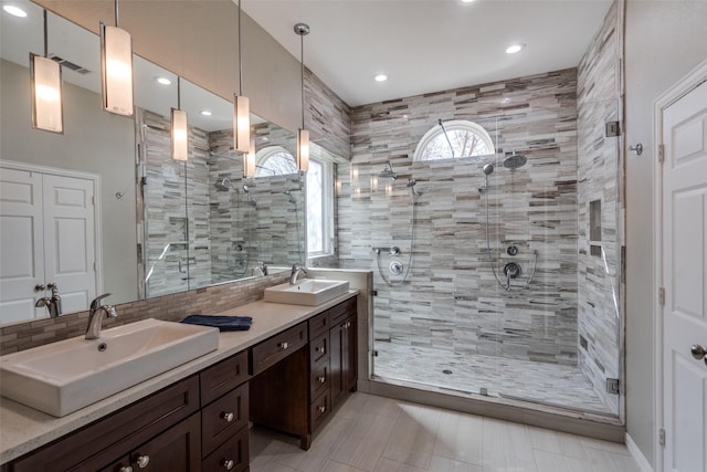 bathroom with double vanity, decorative backsplash, a shower stall, and a sink