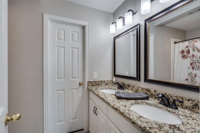 bathroom with double vanity, visible vents, and a sink