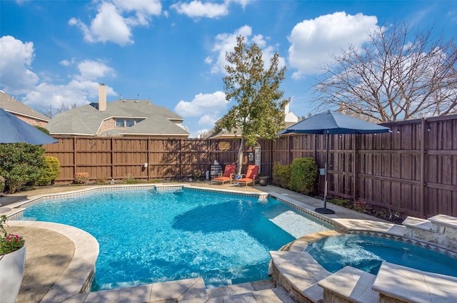 view of swimming pool with a fenced backyard and a pool with connected hot tub